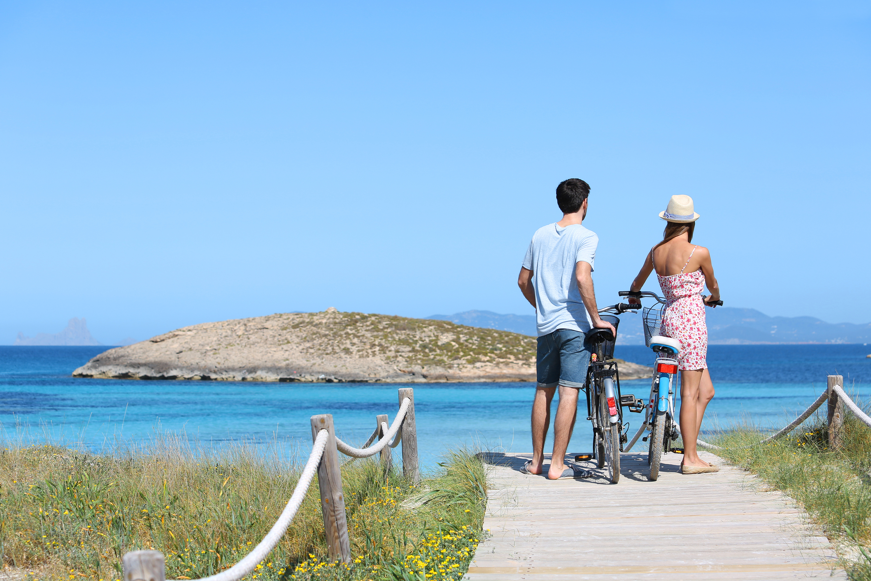 Couple standing by gorgeous beach with bicycles