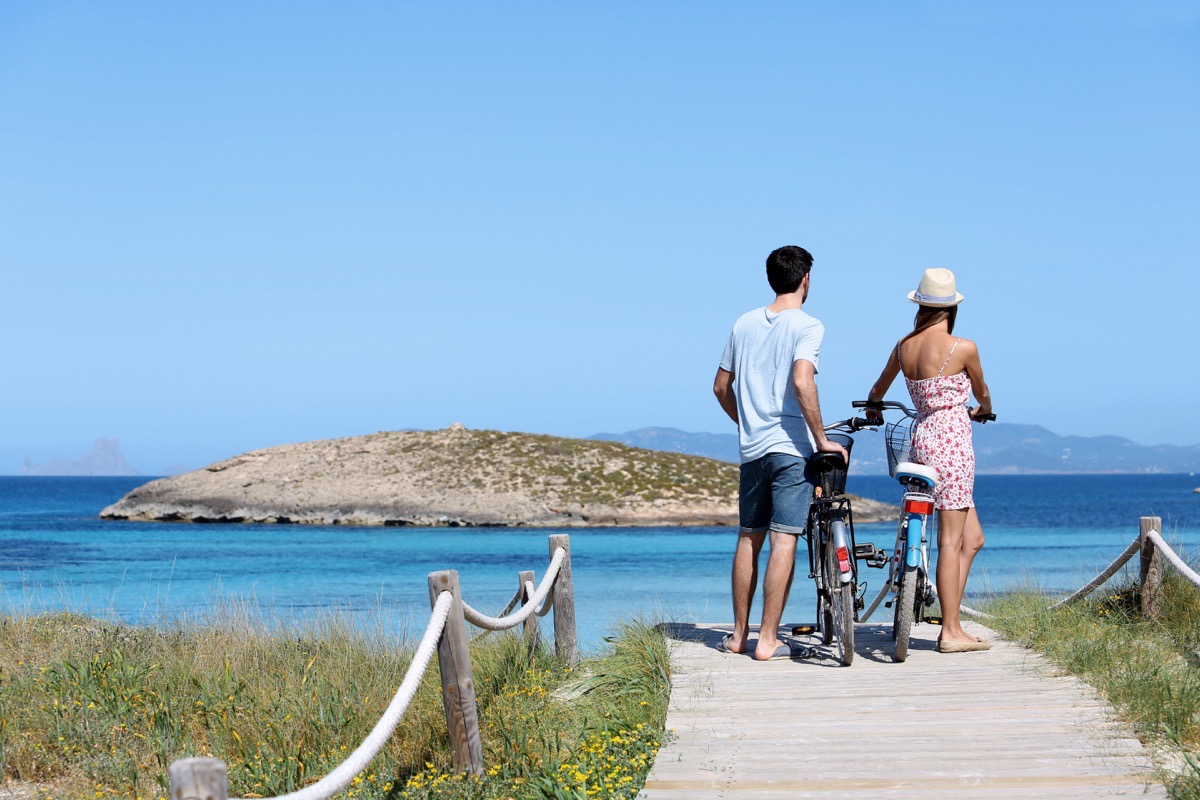 Couple standing by gorgeous beach with bicycles